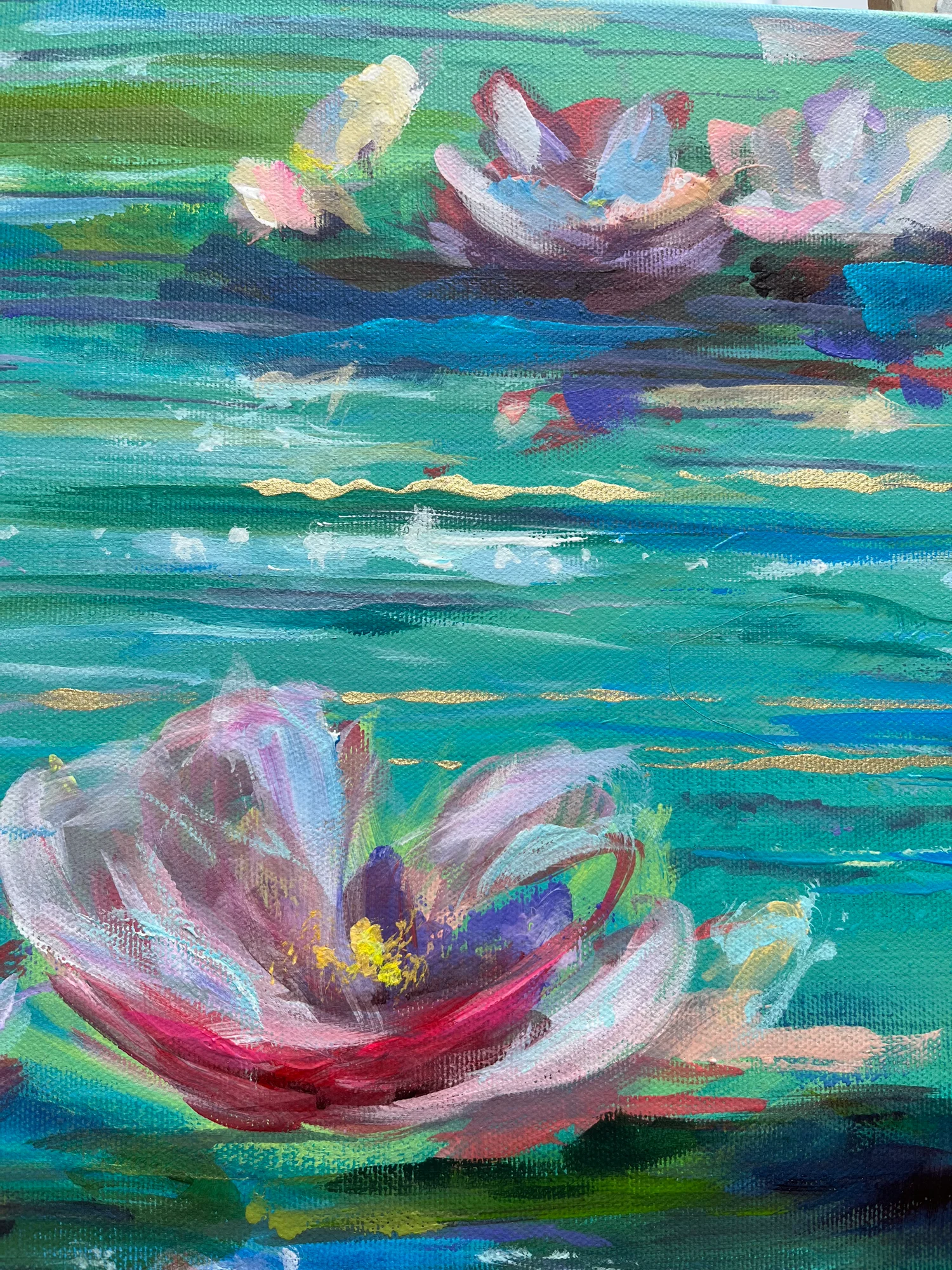 Close detail: one large pale pink water lily with a violet and yellow centre, floating on teal water threaded with gold