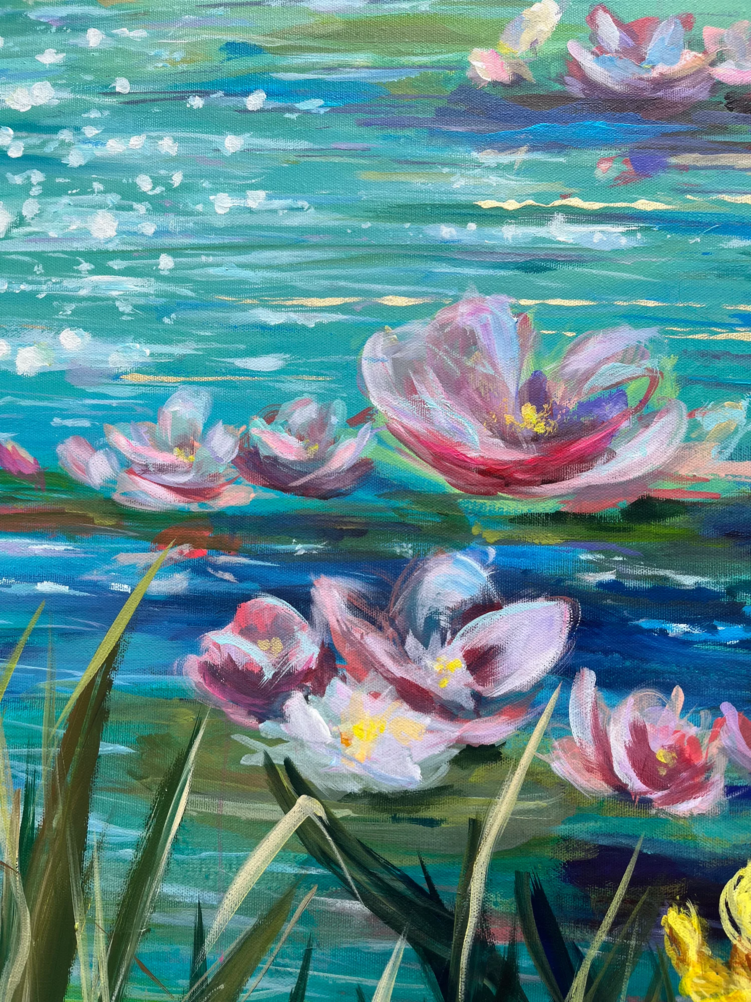 Close detail: a cluster of pink and white lilies across the middle, shimmering turquoise water above, reeds entering from below
